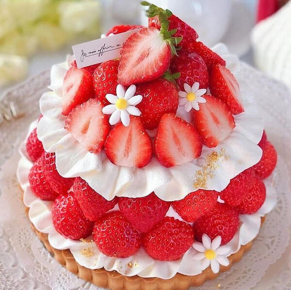 Strawberry Melody - Fresh cut strawberries and hand made candied flowers pressed delicately into house made white chocolate whipped cream on layers atop a white chocolate and strawberry puree tart cake.
