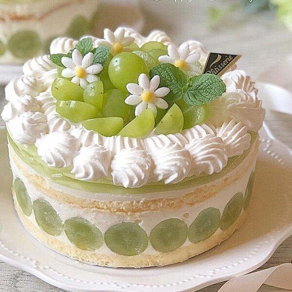 Green Grape Cake - House made whipped frosting filled with fresh green grapes between two thin angel cake layers, topped with more fresh whipped cream, grapes and sugar flowers.