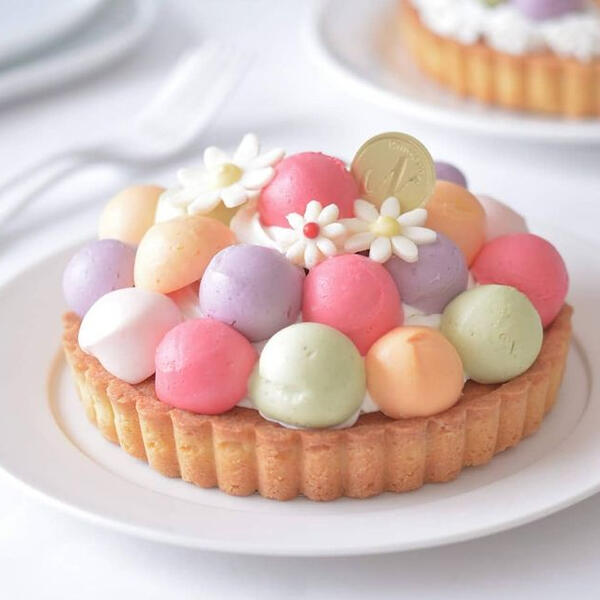 Fruit Salad Tart - Scoops of house-made custard in various fruit flavors including kiwi, blackberry, raspberry and orange topped with sugar flowers on a honey tart cake.