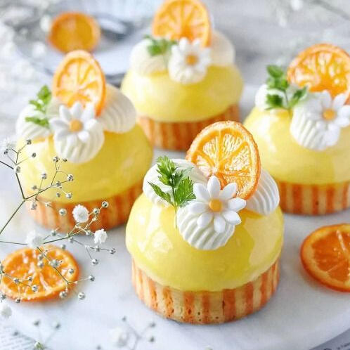 Lemon Custards - Fresh house made lemon custard atop a thick honey lemon striped cake and decorated with min, house made whipped cream, a hand made sugar flower and candied lemon slice.